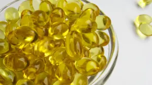 Dzeltenas D vitamīna kapsulas stikla trauciņā uz balta fona, augsts tuvplāns.
