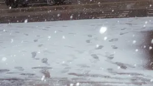 Pēdas sniegā krītošu pārslu laikā, kas simbolizē jauna ceļa sākumu ziemas apstākļos.